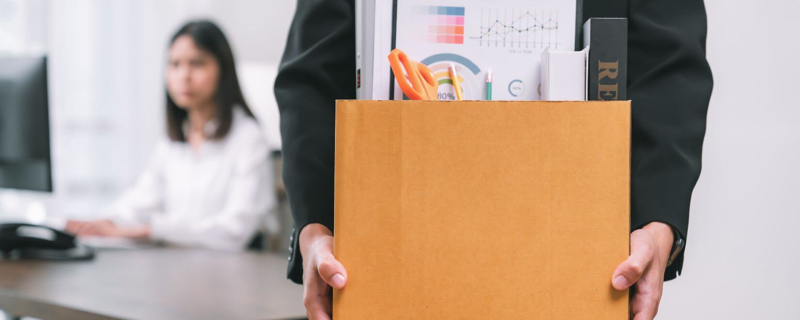 An employee leaving the office holding a box full of belongings